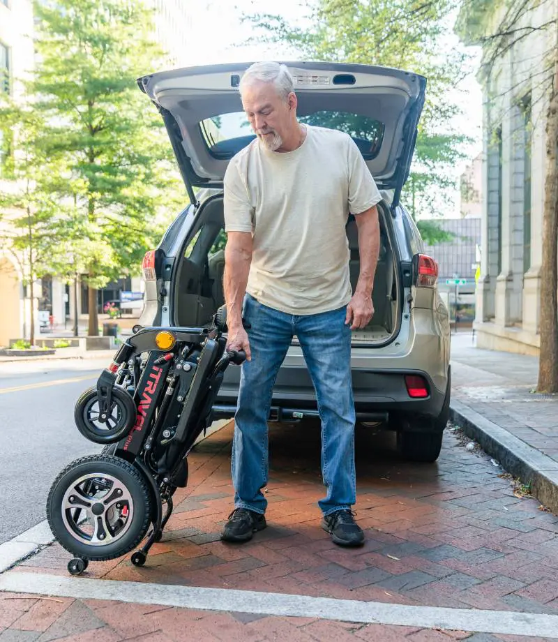 Man unloading an electric scooter from his car.