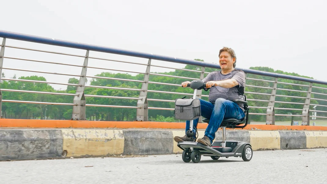 Man with prosthetic legs riding a motorized scooter outdoors.