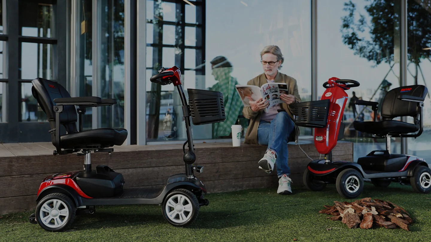 Man reading beside parked mobility scooters outdoors