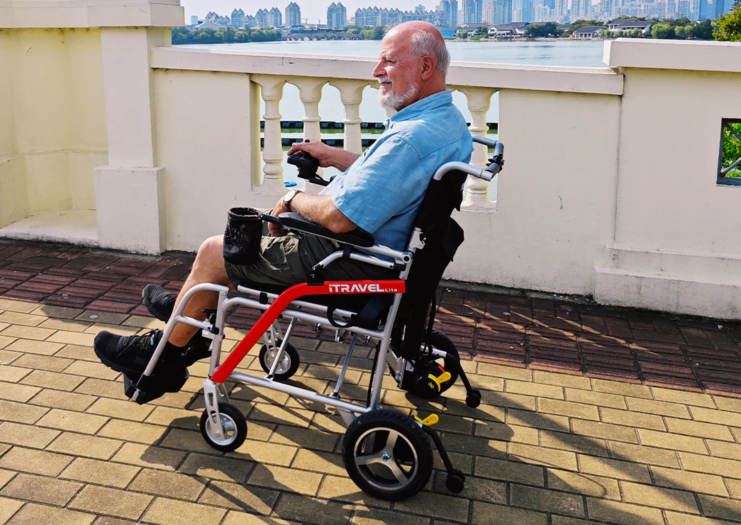 An elderly man with a prosthetic leg sitting in a wheelchair outdoors.