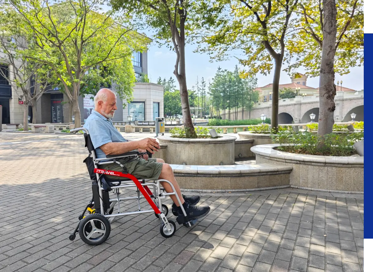 Older man in wheelchair near trees and fountain